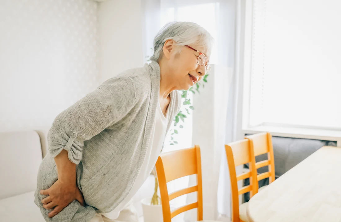 腰をおさえて痛そうな年配女性